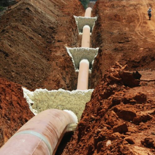 worker walks alongside massive pipeline with foam trench breakers from FSI